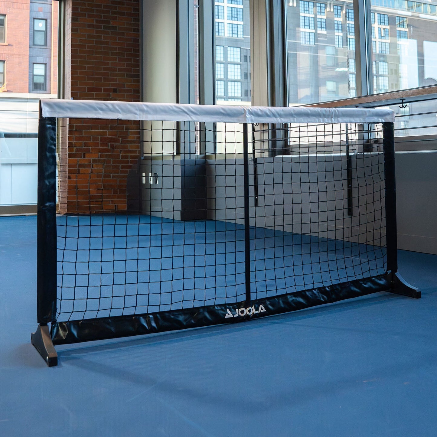 Close up product image of the JOOLA Dink Net at an indoor pickleball court.