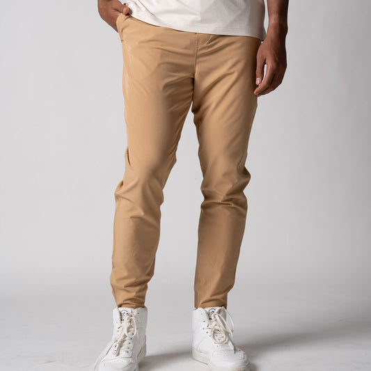 Gray background, close up image of a male model wearing a pair of JOOLA men's club joggers, latte color.