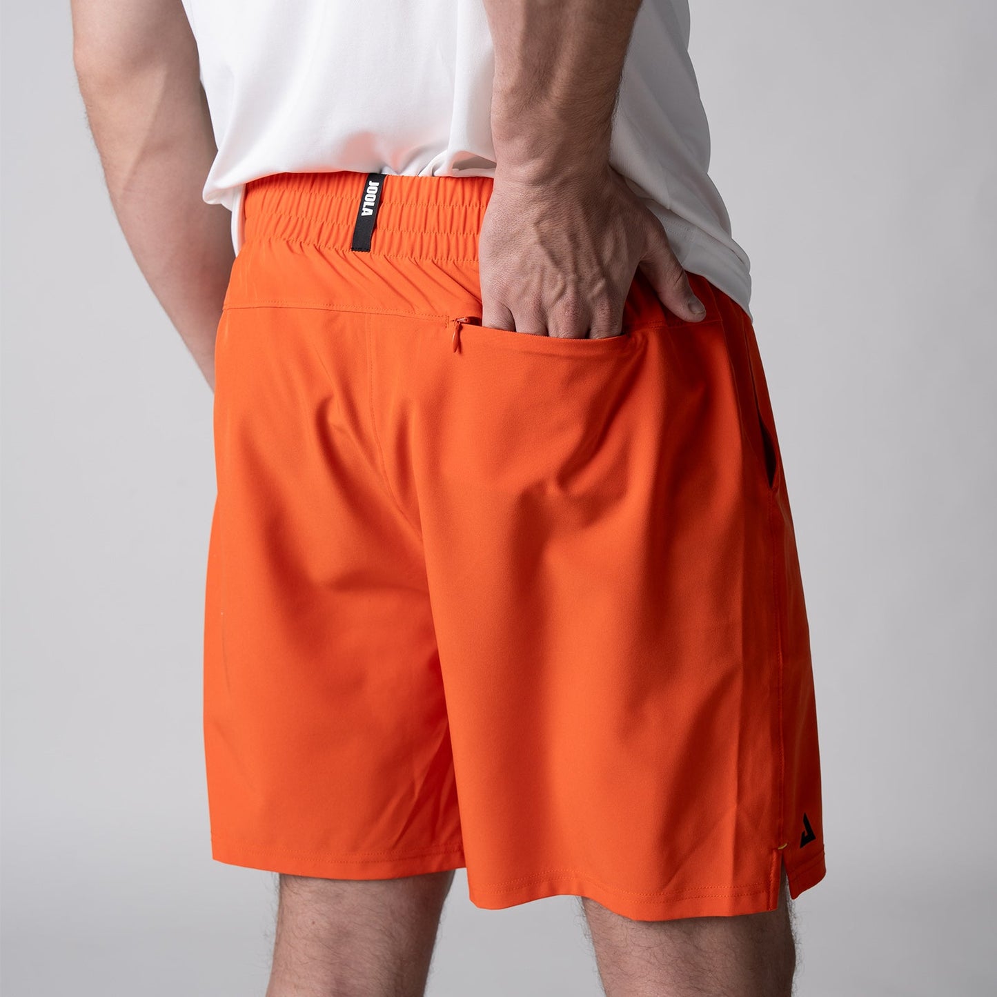 Gray background, close up image of the back of a male model who is wearing the JOOLA Men's Woven Shorts, 7-inch inseam, poppy red color.