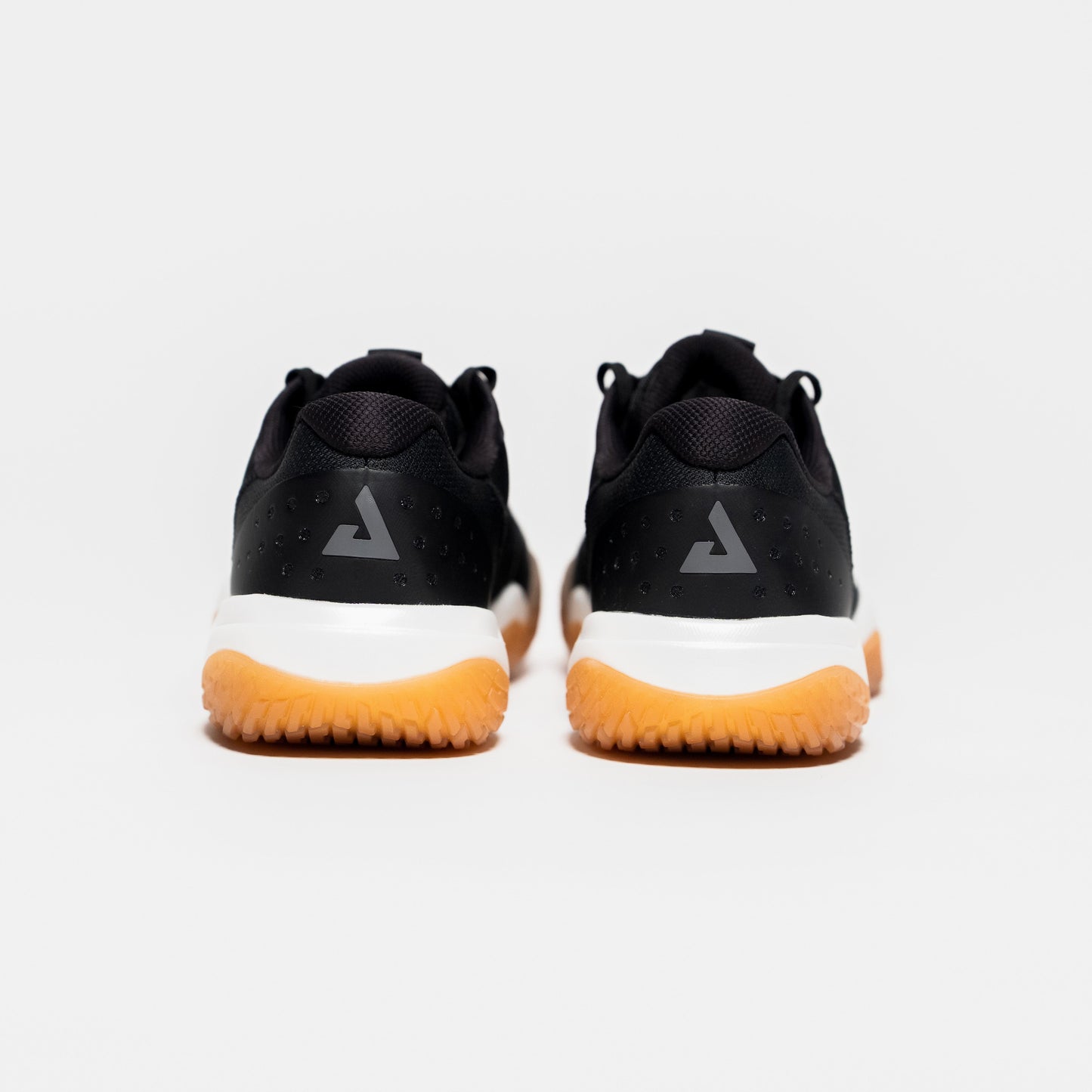 White background, image showing the JOOLA Trinity logo on the back of a pair of JOOLA Men's R4LLy pickleball shoes, black with gum sole.
