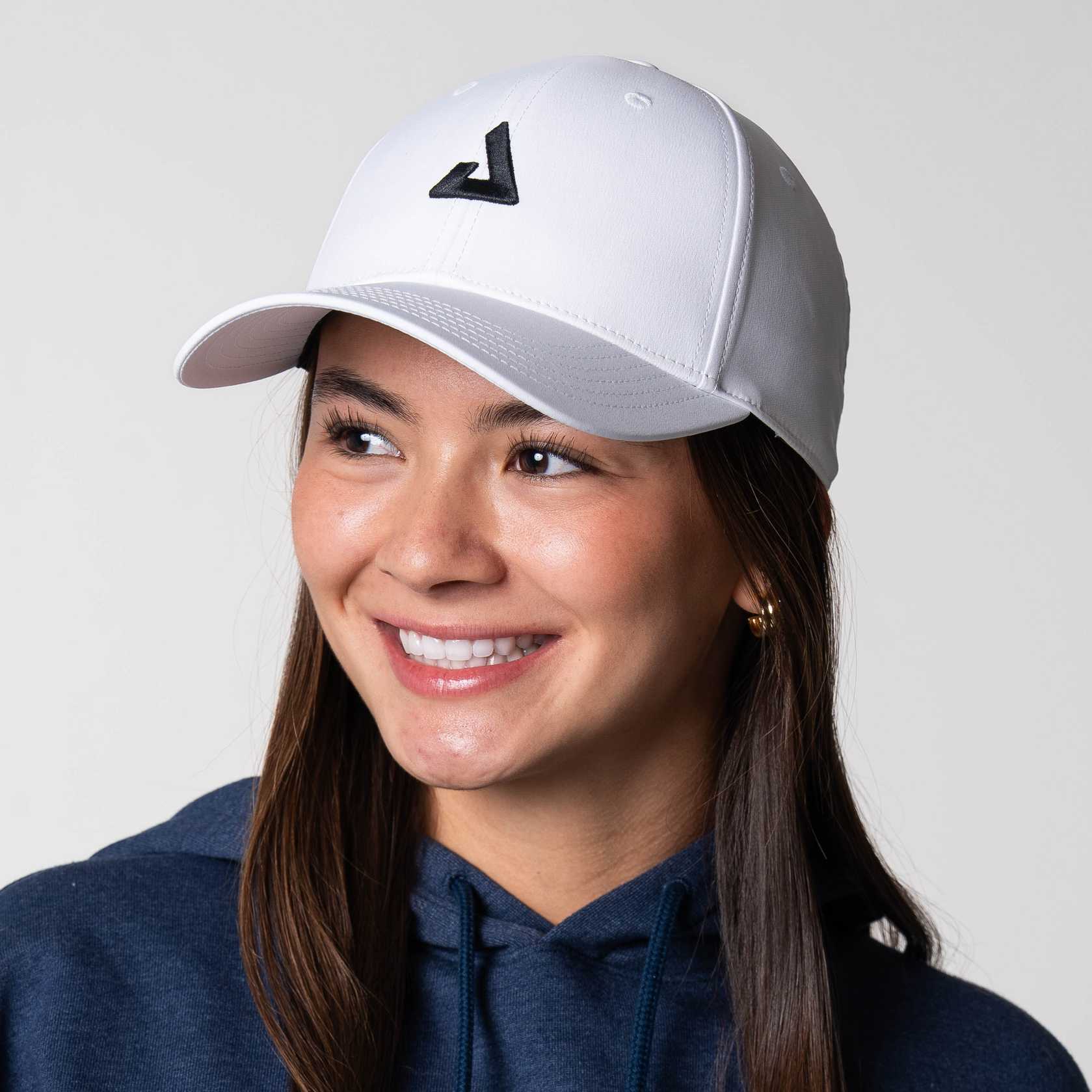 Gray background, image of a female model wearing a JOOLA Essentials Cap, white with black logo.