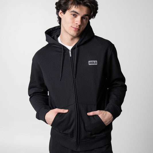 Gray background, image of a male model wearing a zipped up JOOLA Fleece hoodie , black.