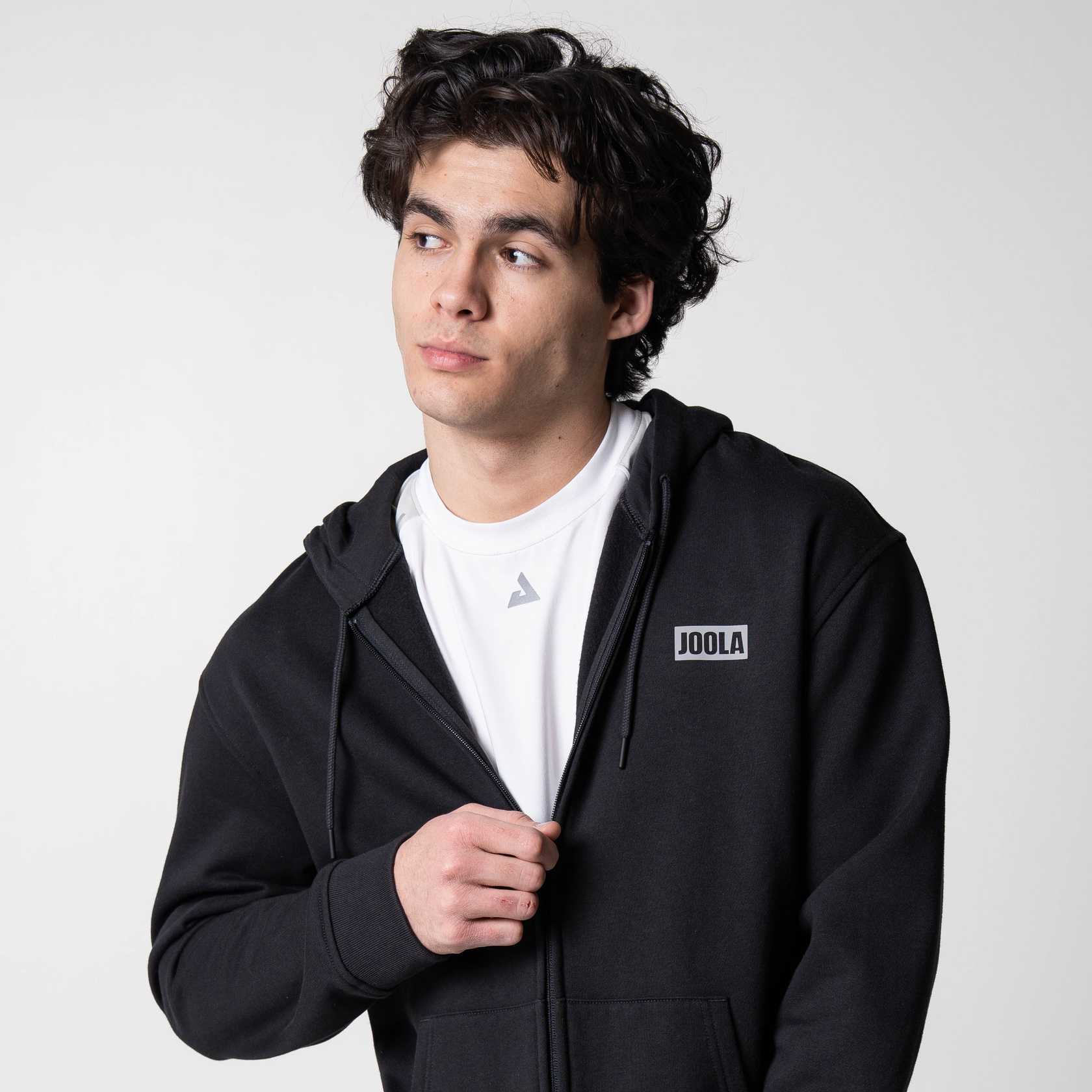 Gray background, image of a male model wearing a black JOOLA Fleece Hoodie.