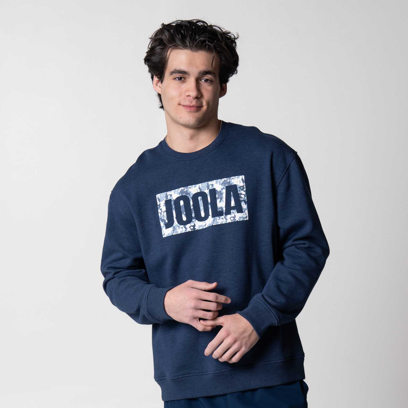Gray background, image of a male model wearing the JOOLA fleece crew, navy Colored.